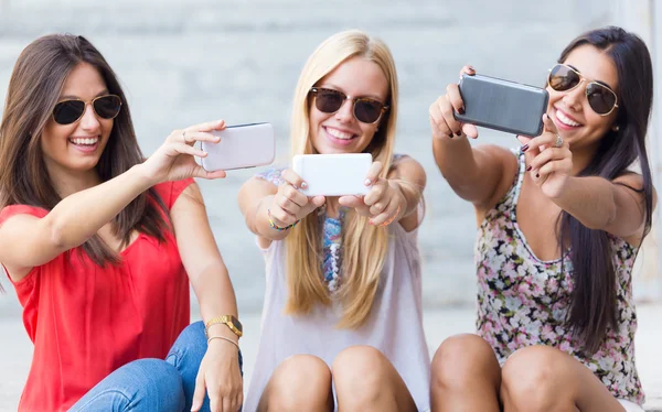 Tres amigos tomando fotos con un smartphone — Foto de Stock