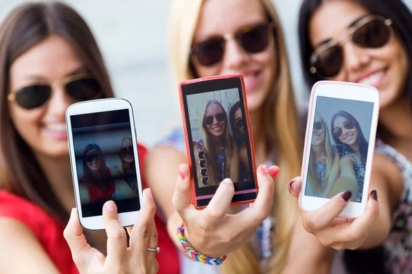 Três amigos tirando fotos com um smartphone — Fotografia de Stock