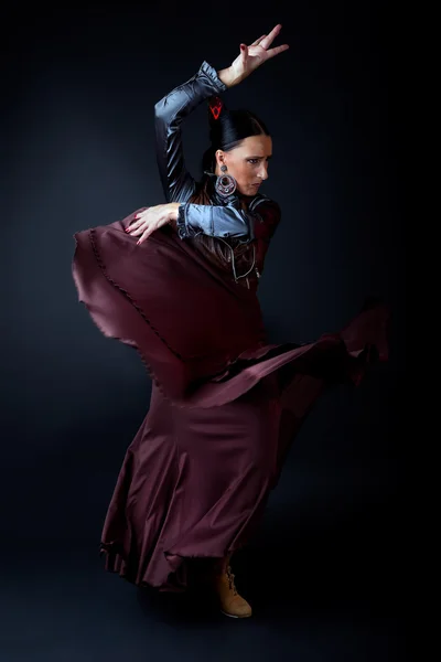 Young flamenco dancer in beautiful dress on black background.