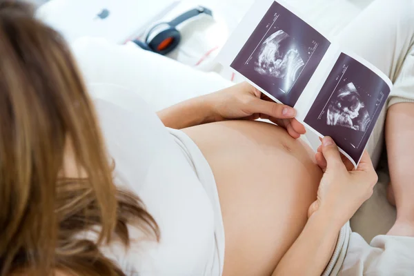 Těhotná žena při pohledu na ultrazvukové vyšetření dítěte — Stock fotografie