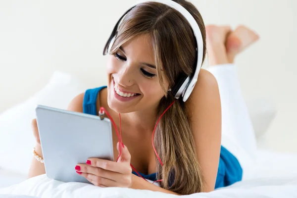 Hermosa chica escuchando música con la tableta en el sofá en casa . — Foto de Stock