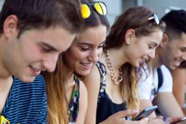 bir grup öğrencinin dersten sonra akıllı telefonlar ile eğleniyor.