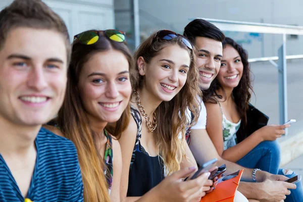 En grupp studenter ha kul med smartphones efter klass. — Stockfoto