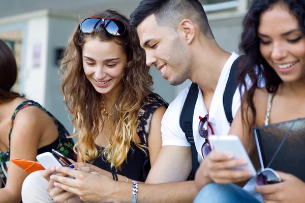 A group of students having fun with smartphones after class. — Stock Photo, Image