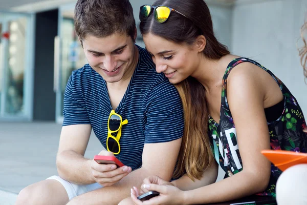 En grupp studenter ha kul med smartphones efter klass. — Stockfoto