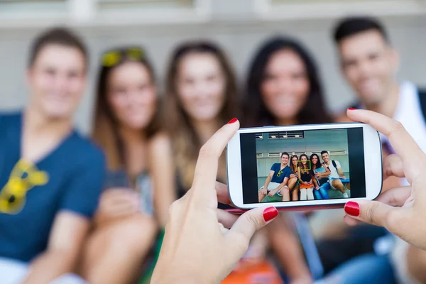 Grupo de amigos tirando fotos com um smartphone na rua . — Fotografia de Stock