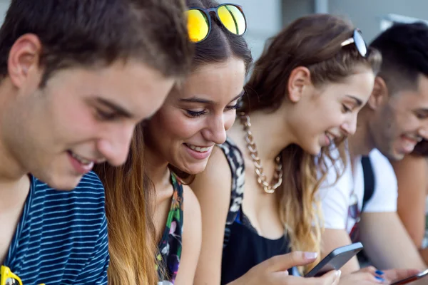 En grupp studenter ha kul med smartphones efter klass. — Stockfoto