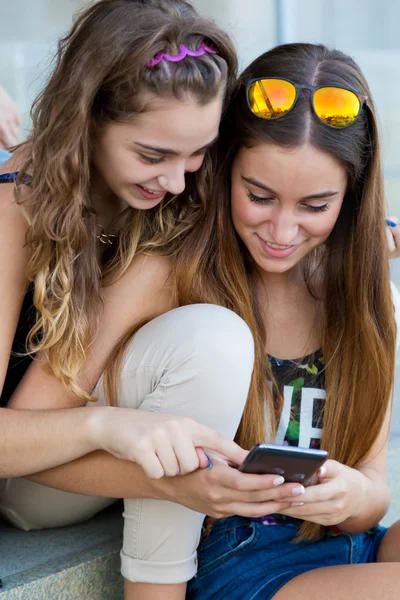 Twee studenten plezier met smartphones na klasse. — Stockfoto