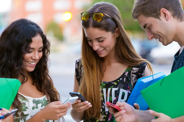 Un grupo de estudiantes divirtiéndose con teléfonos inteligentes después de clase . —  Fotos de Stock