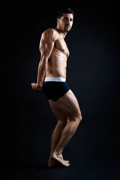 Homem bonito e musculoso em fundo escuro . — Fotografia de Stock