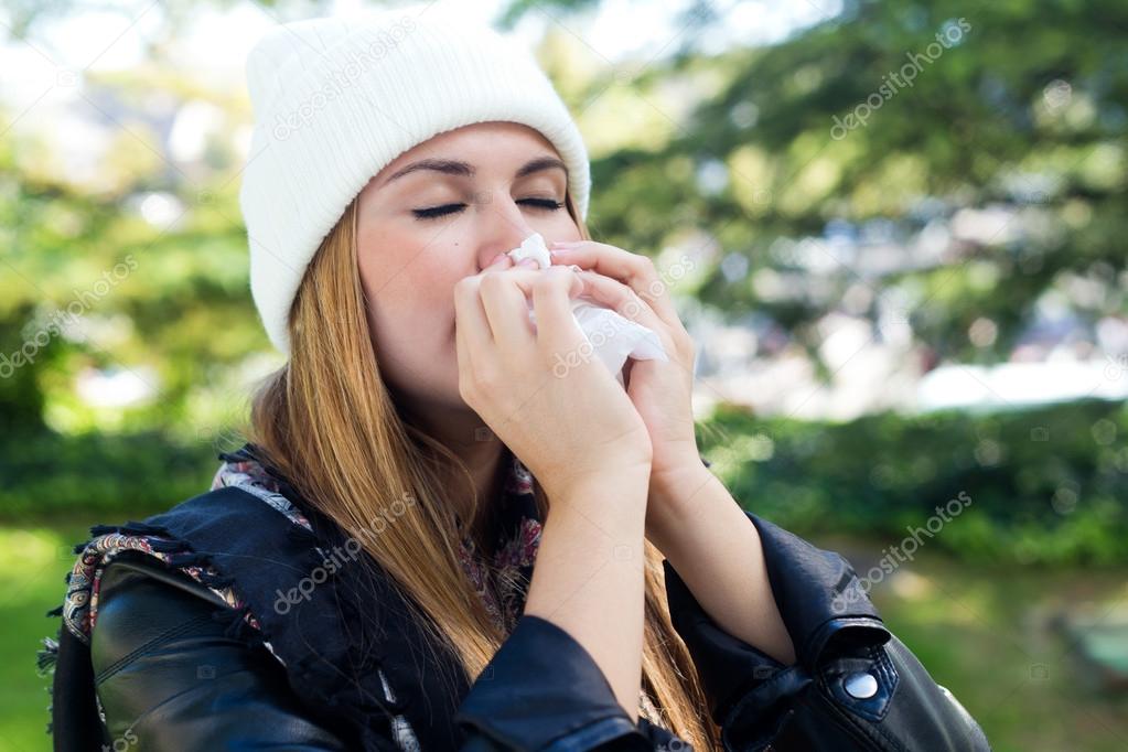 Portrait of beautiful girl with tissue having flu or allergy.