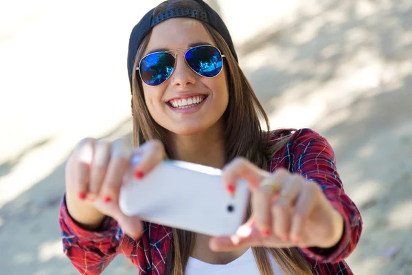 Utomhus porträtt av vacker flicka med en selfie med mobiltelefon i staden. — Stockfoto