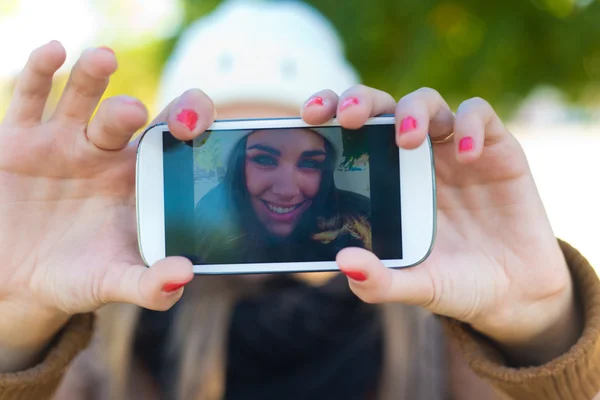 Utomhus porträtt av vacker flicka med en selfie med mobiltelefon i staden. — Stockfoto