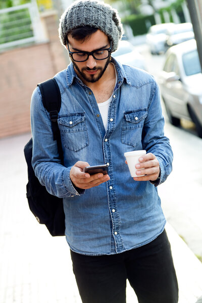 Modern young man with mobile phone in the street.