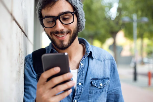 Modern ung man med mobiltelefon på gatan. Stockfoto