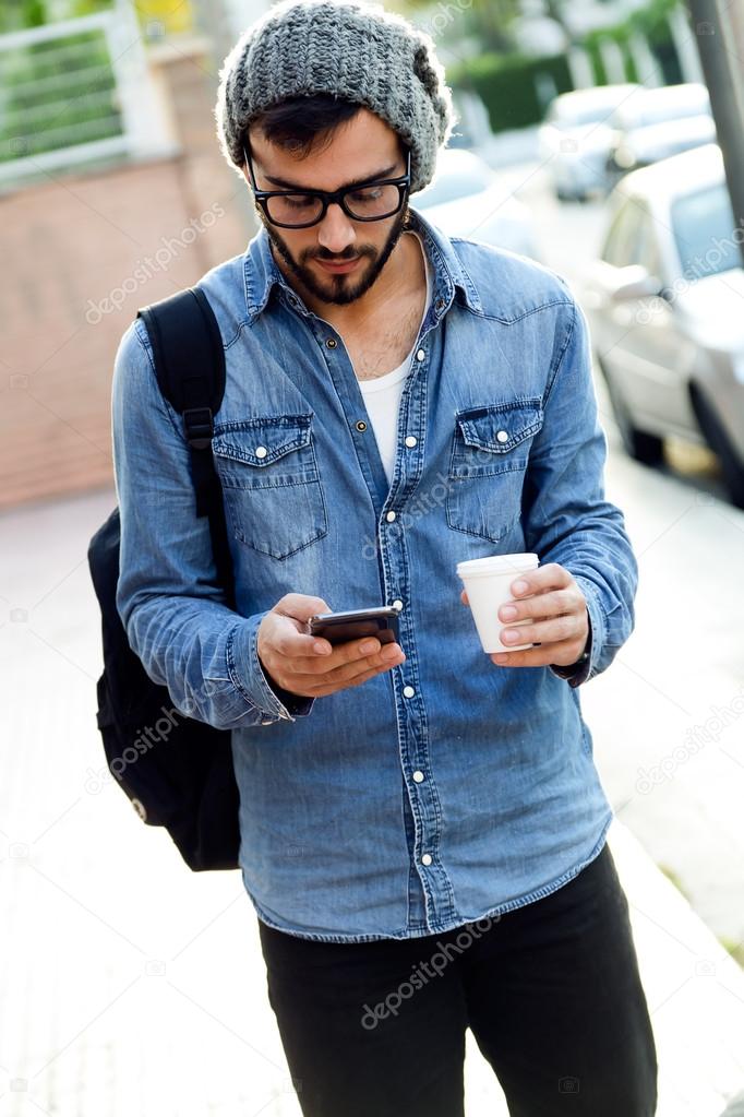 Modern young man with mobile phone in the street.