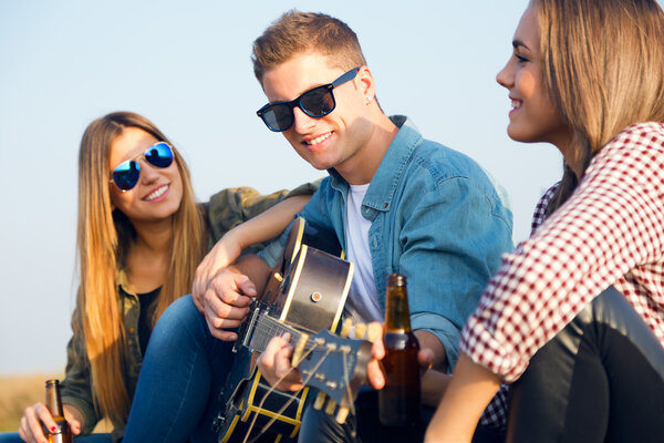 Portrait of group of friends playing guitar and drinking beer.