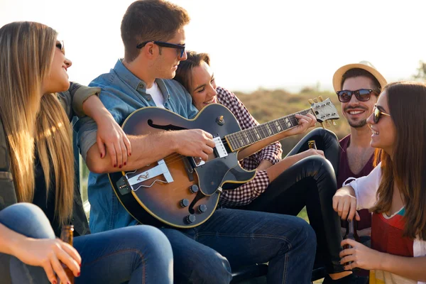 Ritratto di gruppo di amici che suonano la chitarra e bevono birra . — Foto Stock