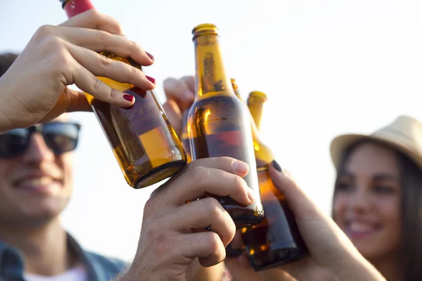 Arkadaşlar bira şişesi ile toasting grup portresi. — Stok fotoğraf