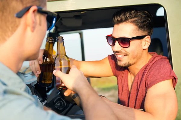 Retrato de dois amigos brindando com garrafas de cerveja no carro . — Fotografia de Stock