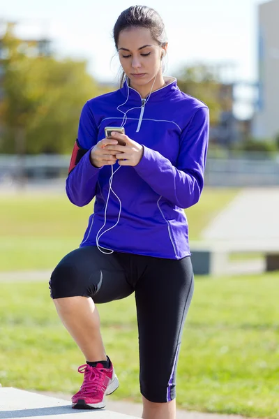 Mooie jonge vrouw luisteren naar muziek na het lopen. — Stockfoto