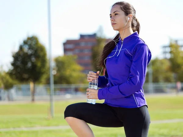 Досить молода жінка п'є воду після бігу . — стокове фото