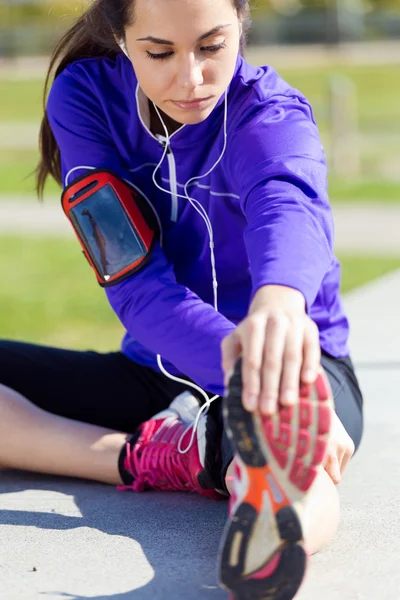 Jovem mulher se alongando e se preparando para correr — Fotografia de Stock