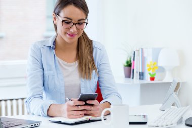 Ofiste cep telefonu kullanan genç ve güzel kadın.