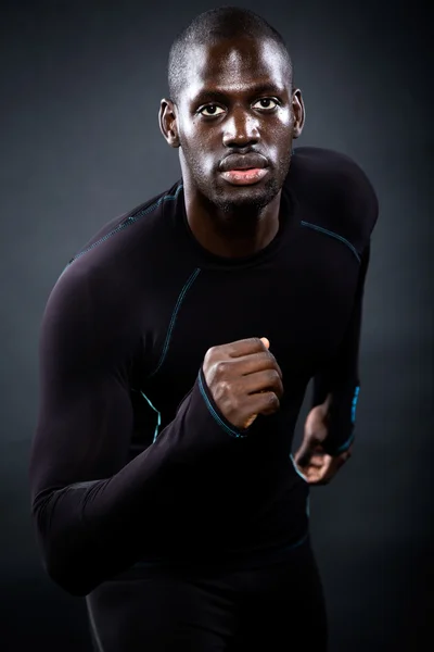 Sportlicher Mann läuft vor schwarzem Hintergrund. — Stockfoto