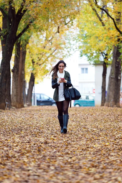 美しい少女の携帯電話で秋景色を歩く. — ストック写真