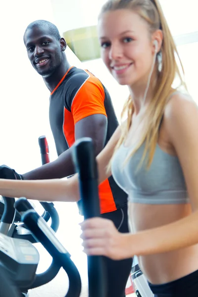 Jeunes avec machine elliptique dans la salle de gym . — Photo