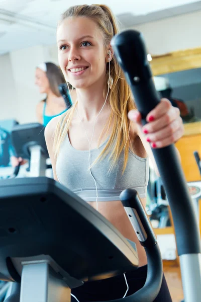 Jóvenes con máquina elíptica en el gimnasio . —  Fotos de Stock