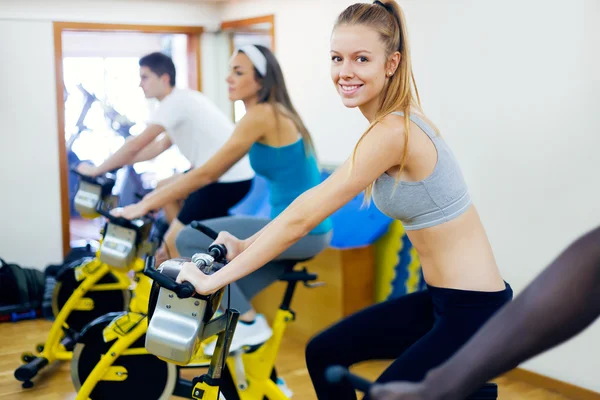 Jugendliche mit Fitnessfahrrad in der Turnhalle. lizenzfreie Stockfotos