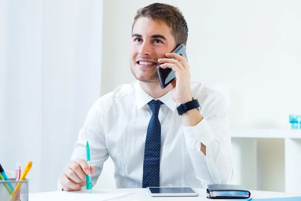 Ung vacker man arbetar i hans kontor med mobiltelefon. — Stockfoto