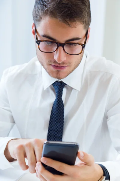 Ung vacker man arbetar i hans kontor med mobiltelefon. — Stockfoto