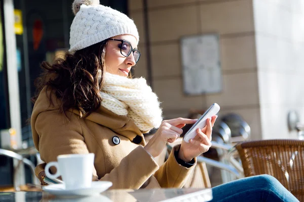 Jonge mooie vrouw met behulp van haar mobiele telefoon in een café. — Stockfoto