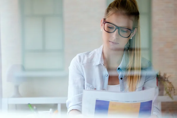 Unga vackra kvinnan läsa tidningen hemma. — Stockfoto