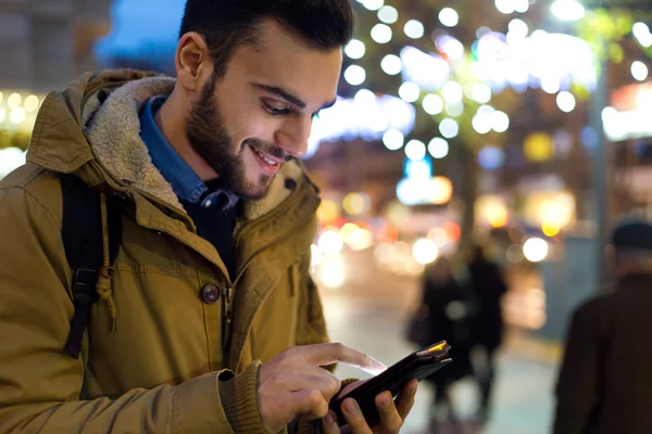 Porträt eines jungen Mannes, der nachts sein Handy auf der Straße benutzt. — Stockfoto