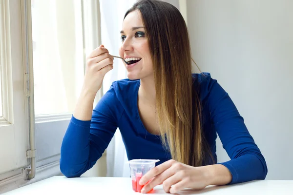 Junge schöne Frau isst Joghurt zu Hause. — Stockfoto