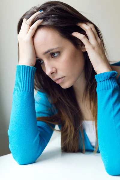 Deprimida jovem mulher sentada em casa . — Fotografia de Stock