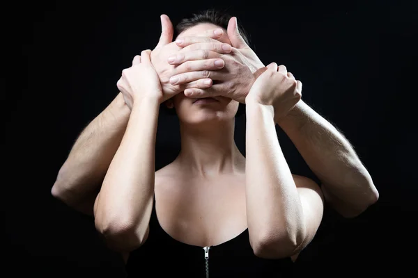 Jeune femme aux yeux couverts par des mains masculines. Notion de submis — Photo