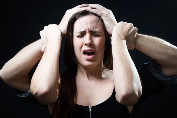 Mujer joven con las manos masculinas presionando su cabeza. Concepto de oppr — Foto de Stock