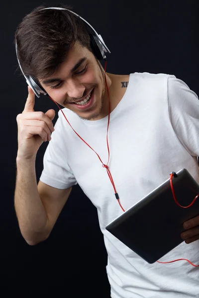 Giovane bellissimo uomo che ascolta musica. Isolato su nero . — Foto Stock