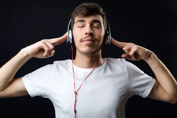 Jonge mooie man luisteren naar muziek. Geïsoleerd op zwart. — Stockfoto