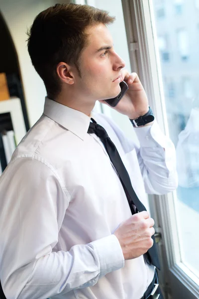 Młody biznesmen za pomocą swojego telefonu komórkowego w biurze. — Zdjęcie stockowe