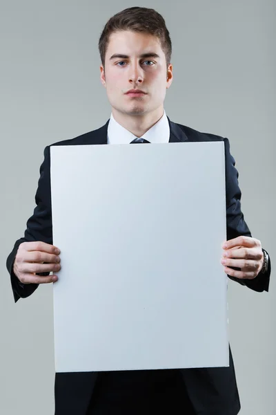 コピースペースを示す空の白い板を持っているビジネスマン. — ストック写真