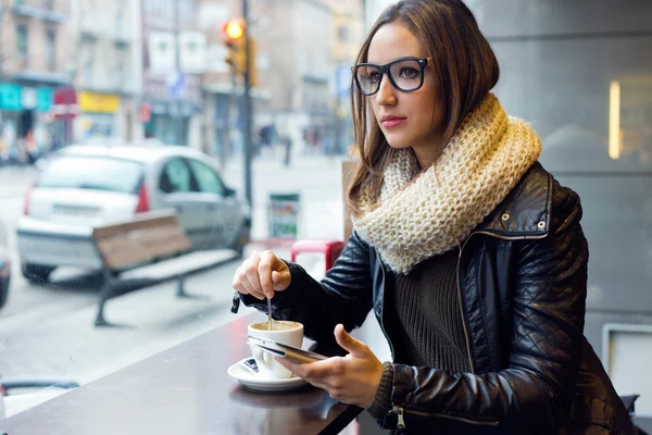 Mooi meisje met behulp van haar mobiele telefoon in café. — Stockfoto