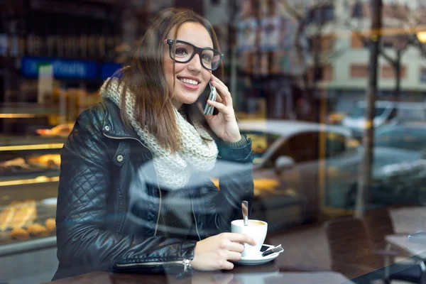 Mooi meisje met behulp van haar mobiele telefoon in café. — Stockfoto