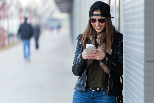 Jonge mooie vrouw met mobiele telefoon in de straat. — Stockfoto