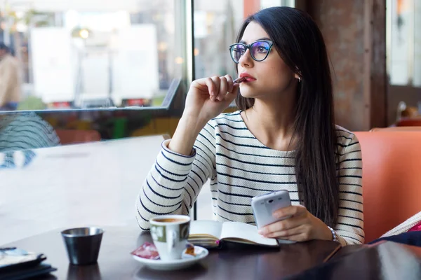 Ung vacker kvinna med hennes mobiltelefon i kaffe. — Stockfoto